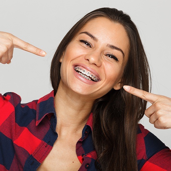 Woman with adult orthodontics pointing to her smile