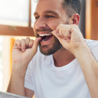 Man smiling while flossing teeth