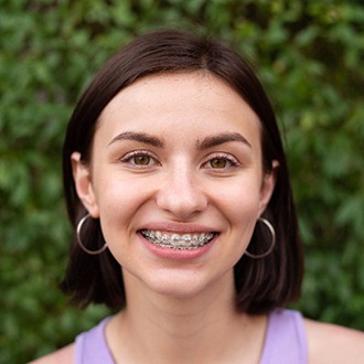 Woman with traditional braces smiling outside