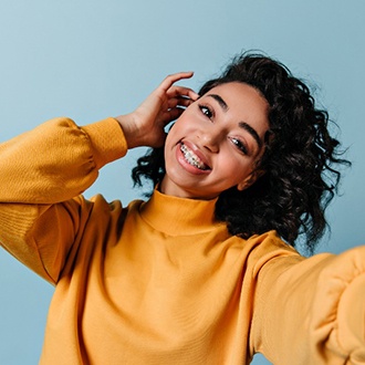 Young woman with braces smiling while taking a selfie