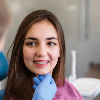 Girl with braces smiling at orthodontist during check-in visit