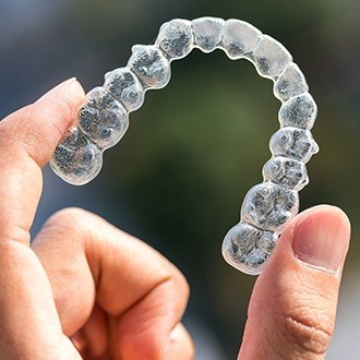 Hand holding an Invisalign tray