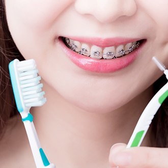 Woman with braces smiling while holding dental tools