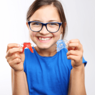 Young girl holding two orthodontic appliances